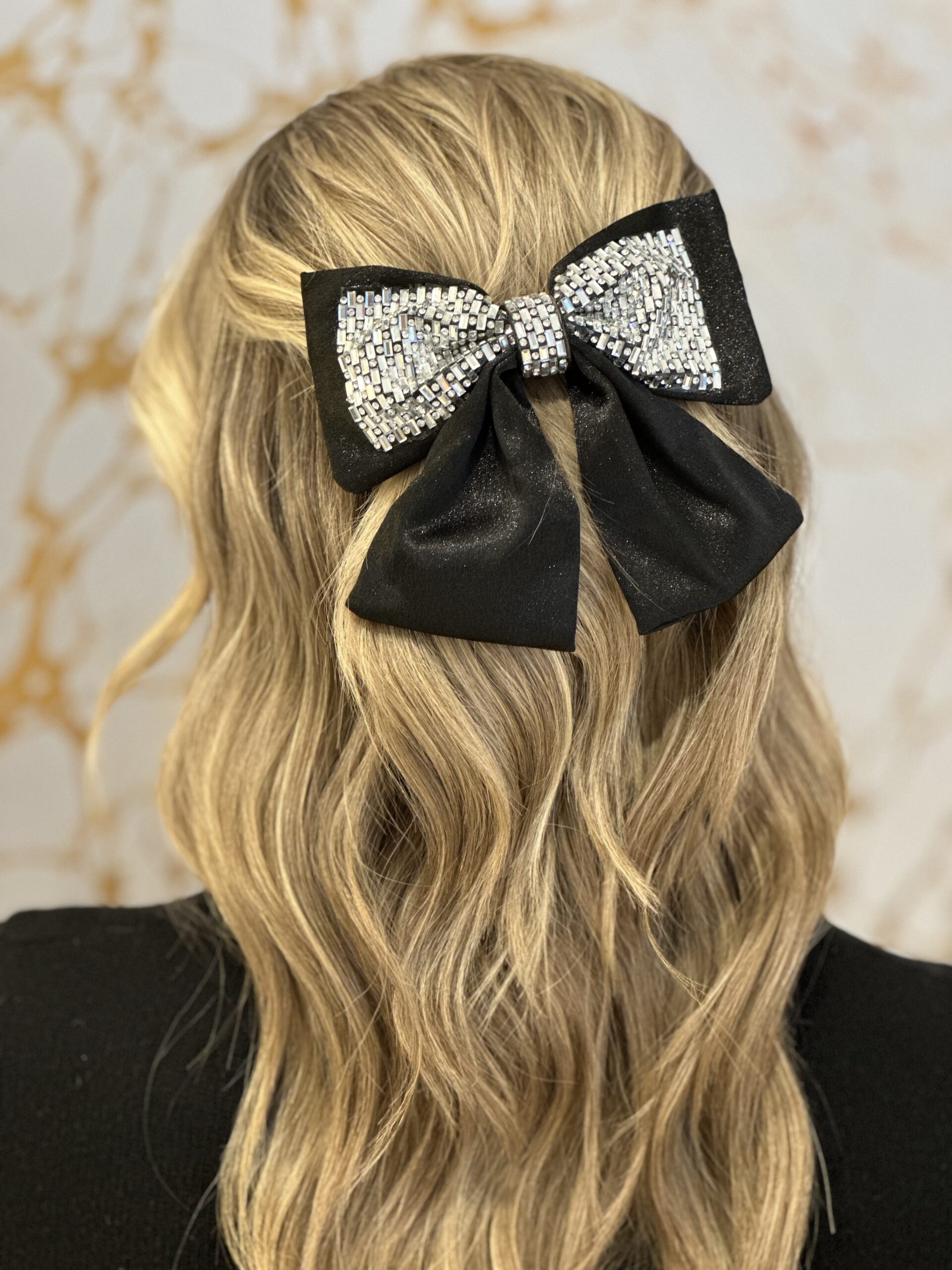 A photo showing the back of a blonde person's head, with a hair bow prominently displayed